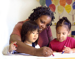 Photo of an afterschool staff member coloring with two young girls.