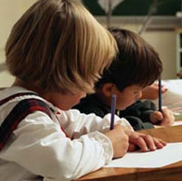 Photo of two children writing at a desk.