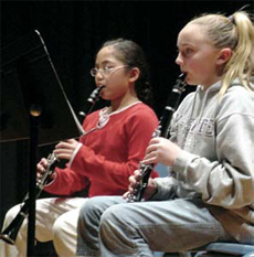 Photo of two girls playing musical instuments.