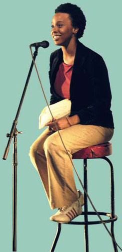 Photo of a woman sitting on a stoll talking into a microphone.