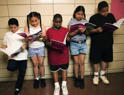 photo of five children standing and reading in a hallway