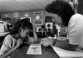 Photo of teacher and student working at a school desk.