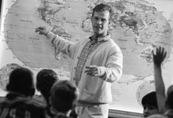 Photo of a teaching showing a world map to a group of students.