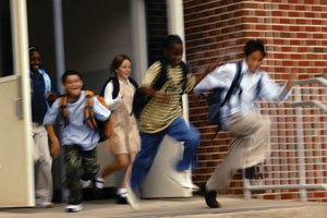 Photo of children running out the school door after the bell rings.
